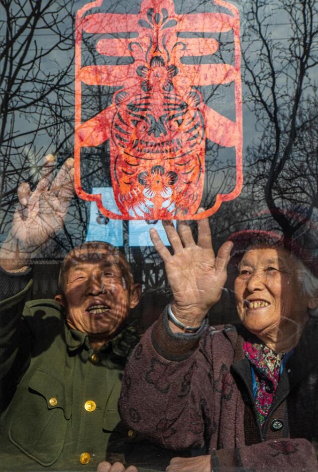 臘月里，霍州市師莊鄉(xiāng)馮南垣村村民師榮光(左)在災后重建的新家里貼窗花。(霍州市委宣傳部供圖)