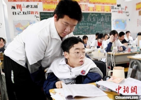 朱金祥(左)把鐘華強(qiáng)放到課堂座位上后，都要把他擺正好，確認(rèn)安全后才回到自己的座位上。 卓忠偉 攝