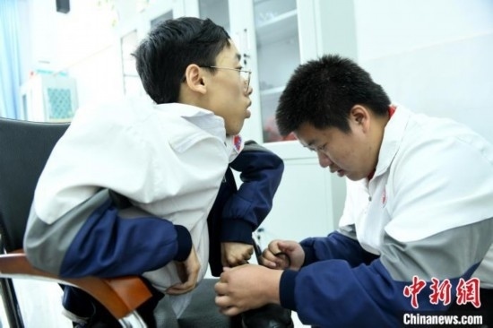 江西省南康中學(xué)北校區(qū)的高三學(xué)生朱金祥(右)正在給鐘華強(qiáng)(左)系好鞋帶。 卓忠偉 攝