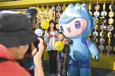 5月7日，在浙江省杭州市湖濱步行街“3D笑臉墻”前，攝影師為游客與杭州亞運(yùn)會(huì)吉祥物之一“宸宸”拍攝合影。