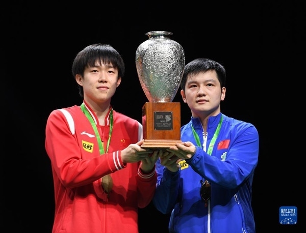 5月27日，樊振東（右）/王楚欽在頒獎(jiǎng)儀式上高舉獎(jiǎng)杯慶祝。當(dāng)日，在南非德班進(jìn)行的2023年世界乒乓球錦標(biāo)賽男雙決賽中，中國(guó)組合樊振東/王楚欽以3比0戰(zhàn)勝韓國(guó)組合張禹珍/林鐘勛，奪得冠軍。新華社記者 李亞輝攝
