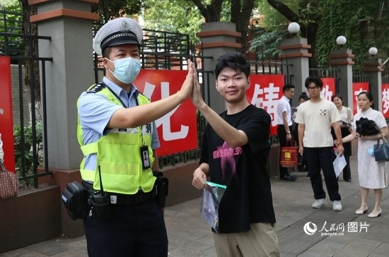6月7日8時(shí)許，武漢中學(xué)考點(diǎn)門口，交警在維護(hù)秩序，并?？忌鸢耦}名。人民網(wǎng)記者 肖璐欣攝