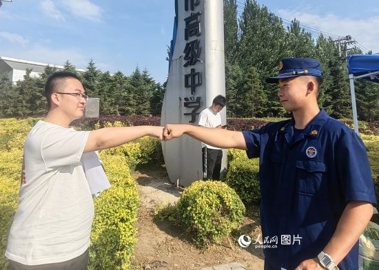 6月7日，遼寧營口老邊區(qū)消防救援大隊(duì)的消防員為高考學(xué)子加油助威。人民網(wǎng)記者 尹柏寒?dāng)z