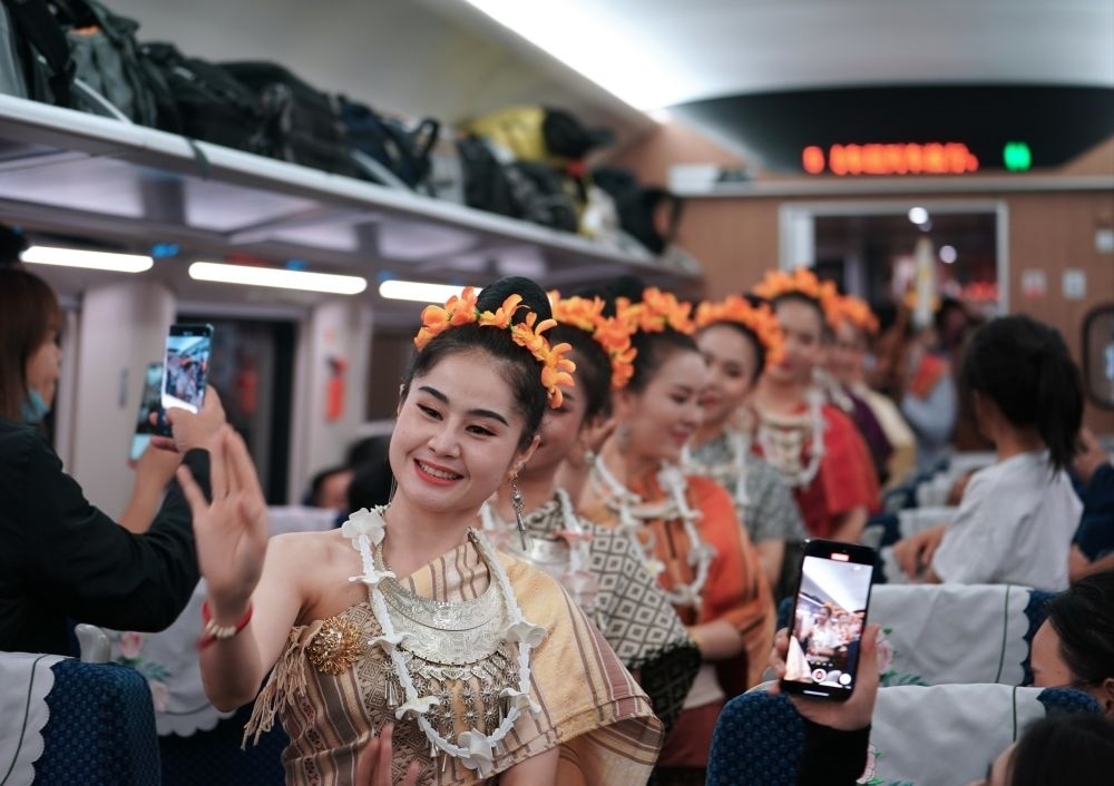 2023年4月13日，老撾工作人員在D887次國(guó)際旅客列車上表演。當(dāng)日，中老鐵路從中國(guó)昆明南站、老撾萬(wàn)象站雙向?qū)﹂_D887次和D888次國(guó)際旅客列車，兩地乘火車可當(dāng)日通達(dá)。中老鐵路是高質(zhì)量共建“一帶一路”的標(biāo)志性工程。新華社記者 邢廣利 攝