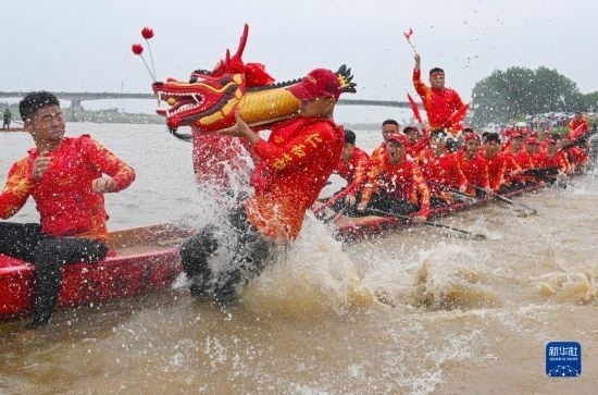6月22日，在湖南省岳陽市湘陰縣湘江臨資口水域，參加龍舟賽的隊(duì)員接“龍頭”下水。