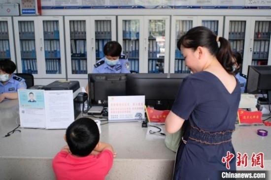 圖為一名家長正在辦證窗口前為孩子申領居民身份證。劉俊聰 攝
