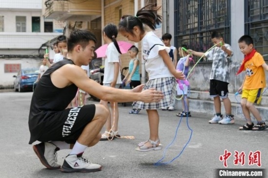 圖為大學(xué)生志愿者在教孩子們學(xué)跳繩。廖光福 攝