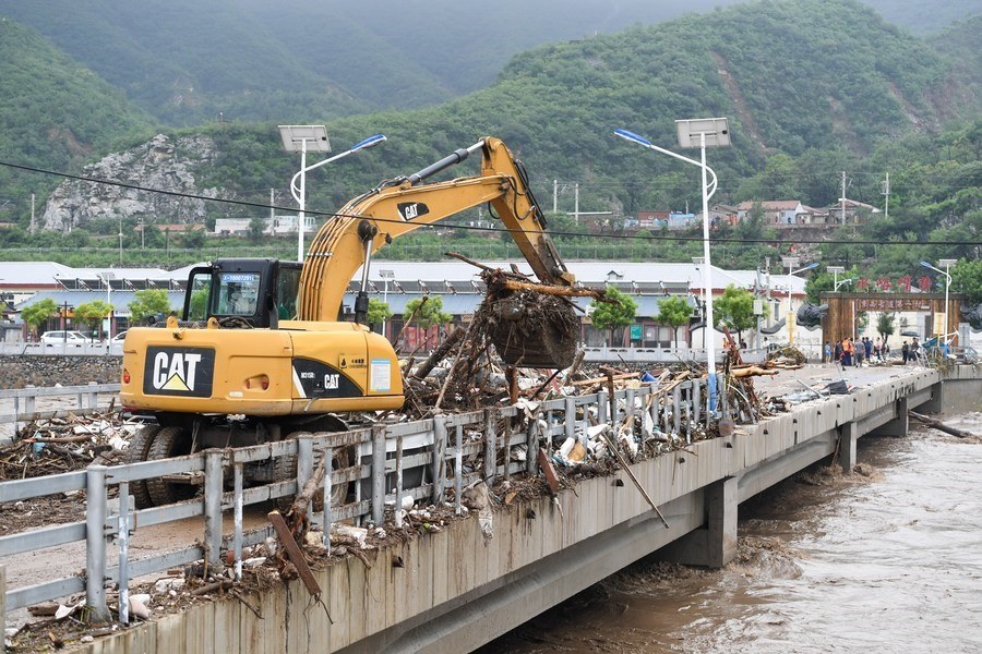 8月1日，在北京市門頭溝區(qū)水峪嘴村村口，一臺挖掘機(jī)在清理阻斷橋梁交通的雜物。目前該條道路已經(jīng)疏通完成。新華社記者 鞠煥宗 攝