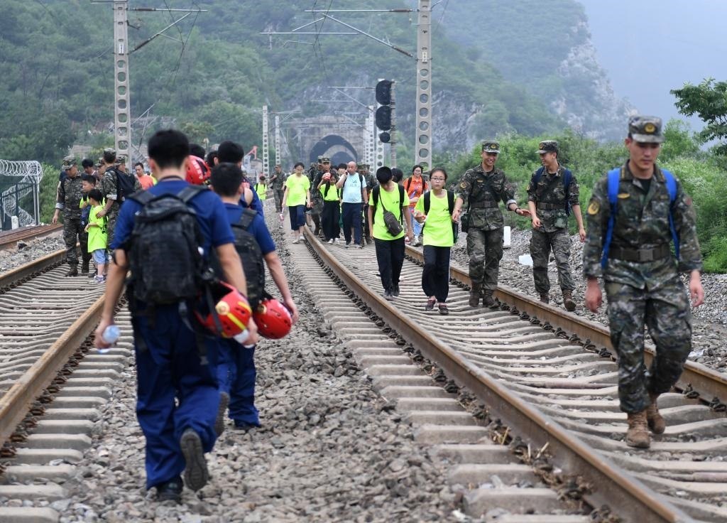 8月2日，部分滯留在北京市門頭溝山區(qū)受困列車的旅客，在救援人員幫助下前往轉(zhuǎn)運客車。新華社記者張晨霖 攝