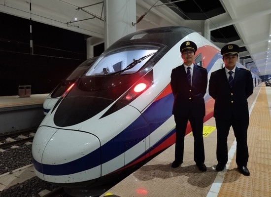 劉銀能（右一）與中國師父鄔俊鴻在動車組前合影。受訪者供圖