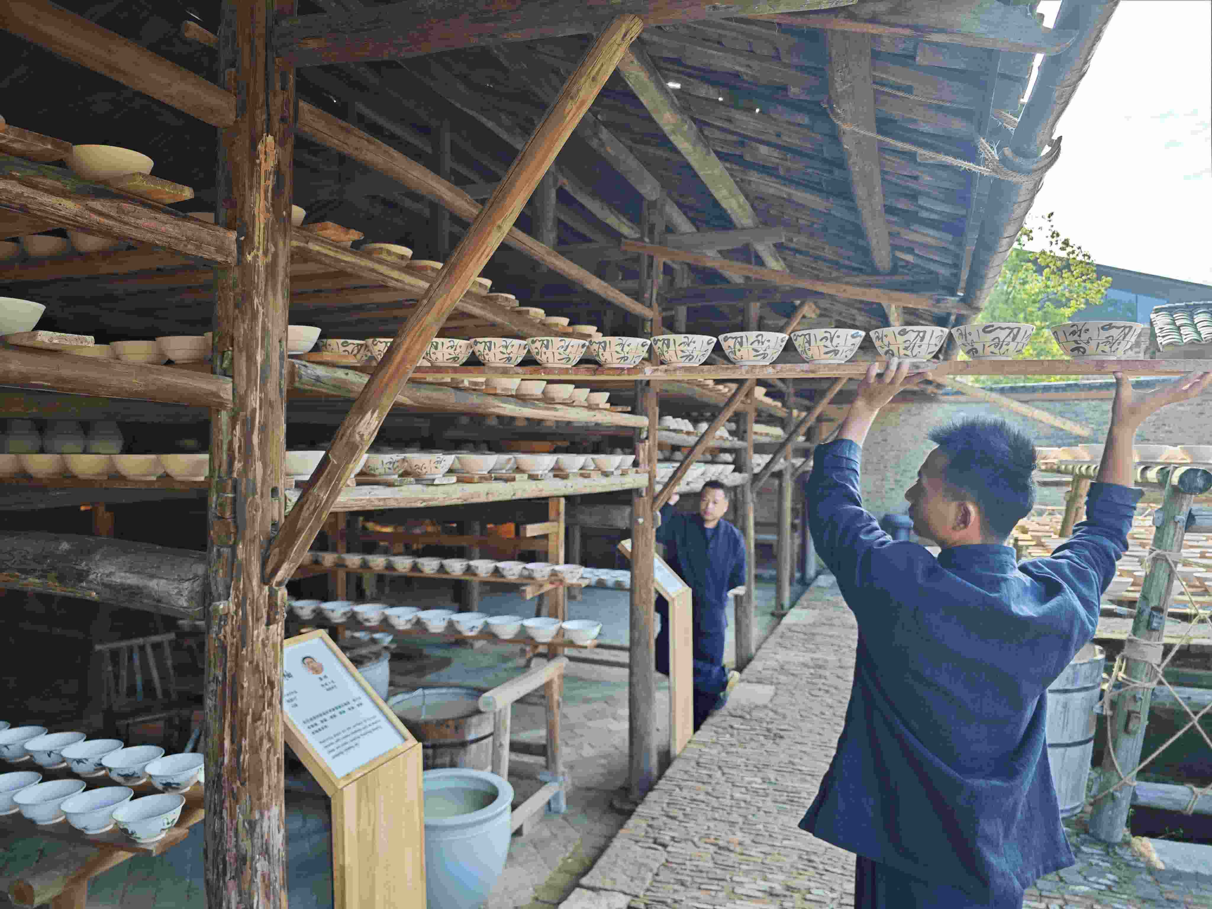 △陶陽里歷史文化街區(qū)里，工匠將陶瓷工藝品放到架上晾干。（總臺央視記者彭漢明拍攝）