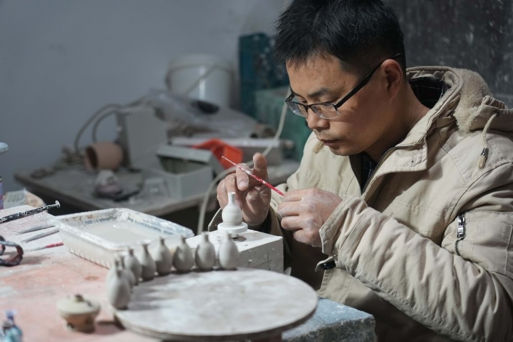 ↑2021年12月15日，來(lái)自安徽的王文化在制作微型陶瓷作品，他來(lái)景德鎮(zhèn)已有十多年時(shí)間。