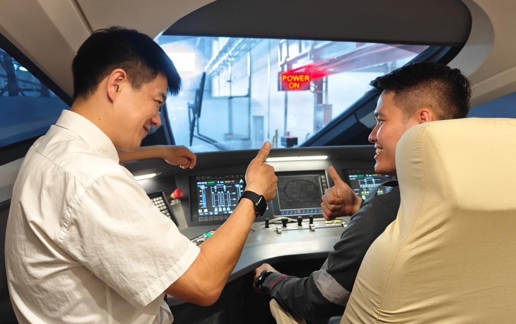 8月25日，在印度尼西亞萬隆的雅萬高鐵德卡魯爾動車所內(nèi)，中國師傅穆振（左）在向印尼火車司機塞蒂亞萬講解動車組出庫前的上電作業(yè)。