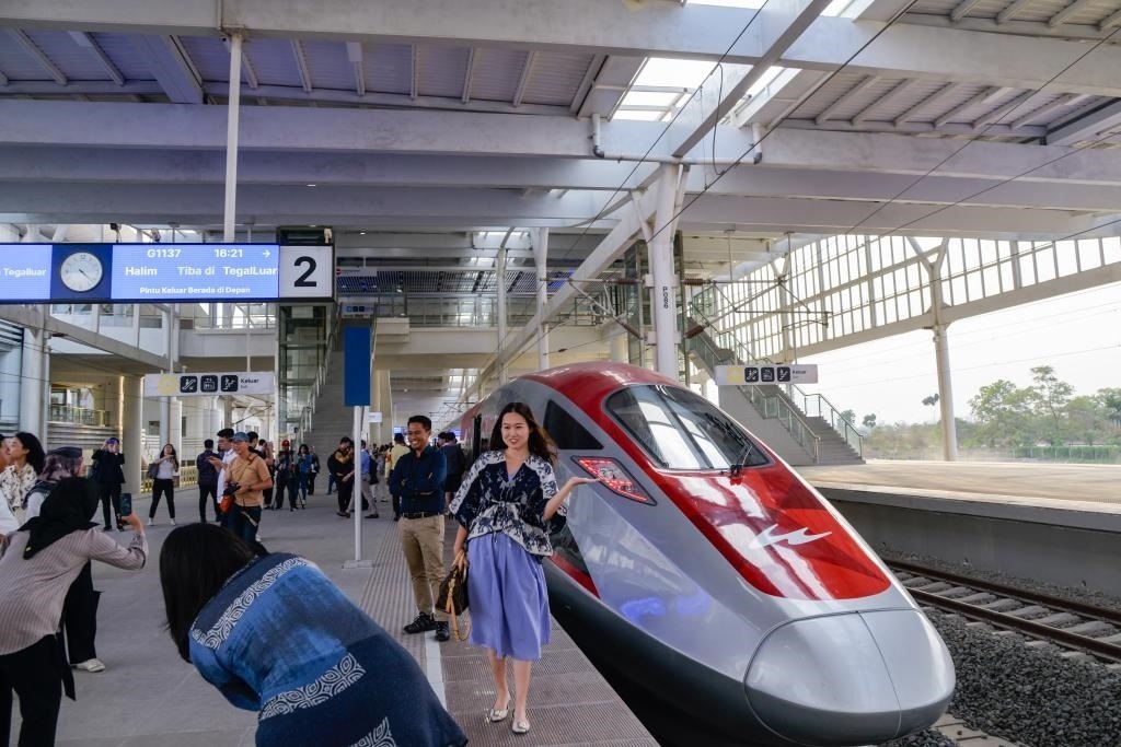 10月17日，在印度尼西亞萬隆德卡魯爾站，乘客在站臺上和雅萬高鐵高速動車組列車合影。
