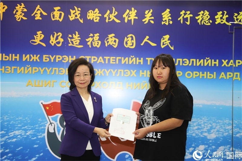 11月10日，沈敏娟大使向蒙古國(guó)公民尼亞姆庫(kù)（右）頒發(fā)最后一份領(lǐng)事認(rèn)證書。人民網(wǎng)記者 霍文攝