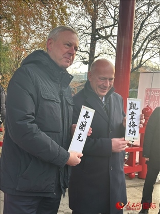 柏林市長韋格納（右）、動物園監(jiān)事會主席布魯克曼（左）手持中國文化中心工作人員現(xiàn)場手書的中文名字。人民網(wǎng)記者 徐馨攝