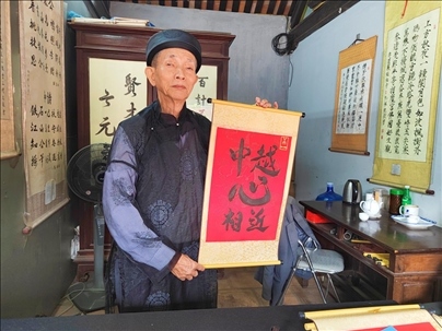 越南首都河內(nèi)文廟內(nèi)，阮明珠展示“中越心相近”書法作品。