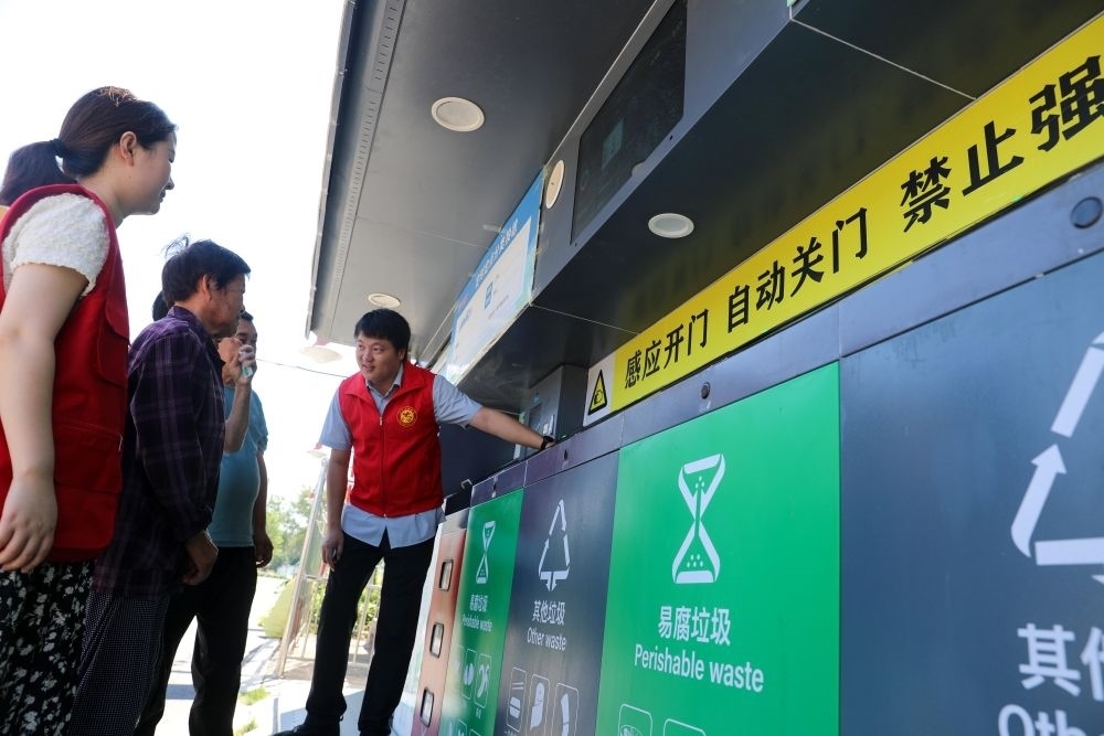 在安徽省合肥市長(zhǎng)豐縣莊墓鎮(zhèn)棗林社區(qū)，志愿者指導(dǎo)居民使用智能垃圾分類(lèi)回收設(shè)備（2023年9月1日攝）。新華社記者 曹力 攝