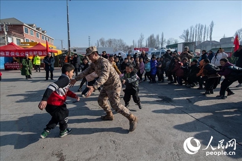 12月22日，在積石山縣大河家鎮(zhèn)大河村安置點，陸軍76集團軍某旅官兵通過游戲方式，對小朋友進行災后心理疏導。人民網(wǎng)記者 翁奇羽攝