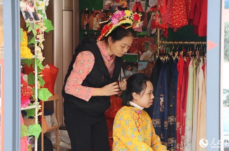 泉州府文廟附近，一名店主正為過路游客梳理頭發(fā)以佩戴“簪花圍”。人民網(wǎng) 黃東儀攝