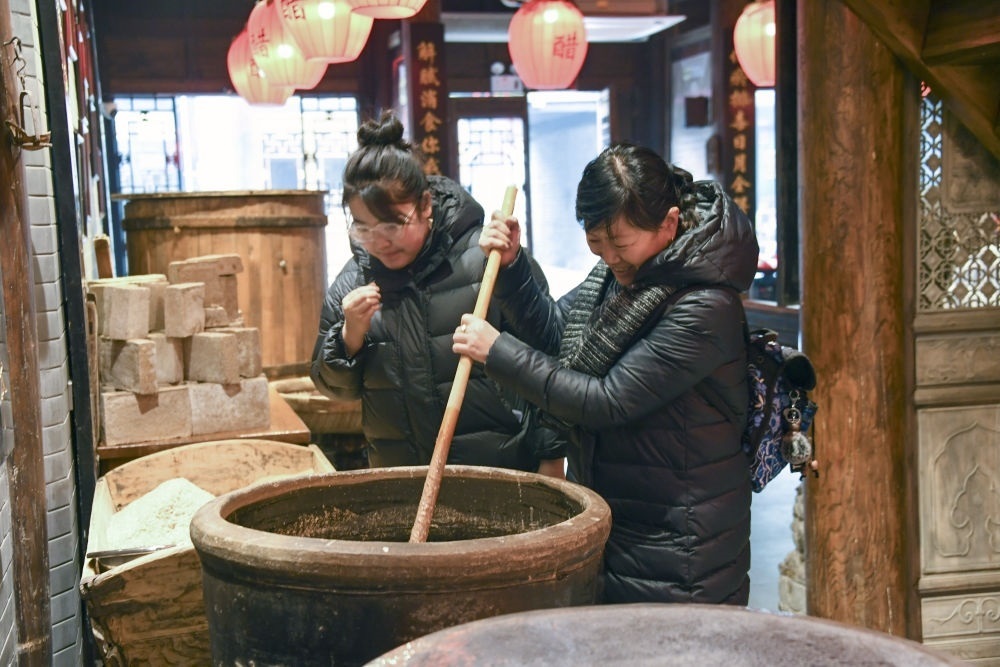 游客在平遙古城東湖老醋坊內(nèi)體驗陳醋發(fā)酵打耙（2022年1月28日攝）。新華社發(fā)（梁生仁攝）