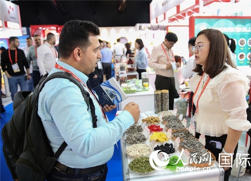 圖為一家中國干果參展企業(yè)代表與采購商洽談。人民網(wǎng) 塔里克·易卜拉欣攝