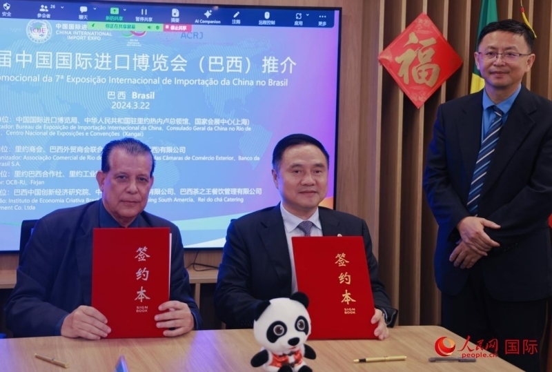 巴西外貿商會聯(lián)合會會長阿代爾·羅伯托（左）與中國國際進口博覽局副局長吳政平（中）現(xiàn)場簽訂協(xié)議。人民網記者 宋亦然攝