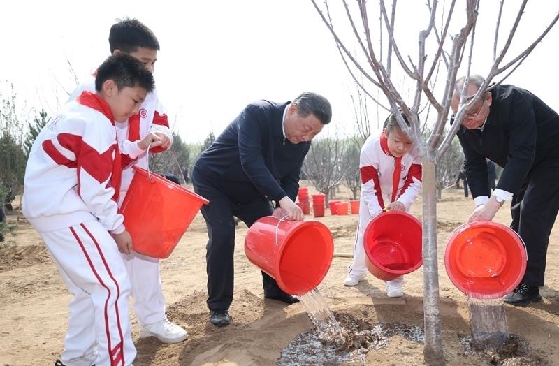 2024年4月3日，習(xí)近平總書記同少先隊員一起給剛栽下的樹苗澆水。