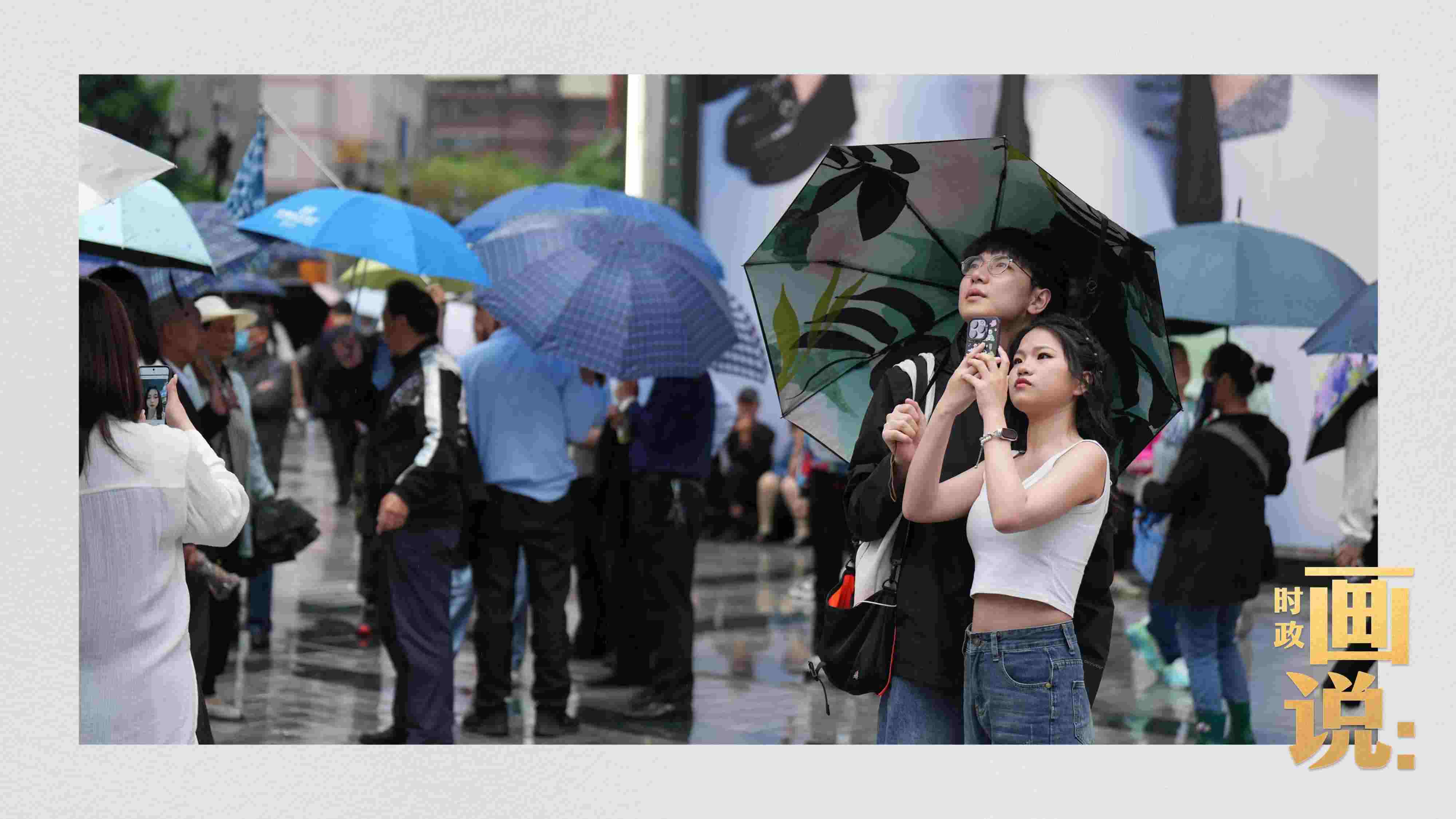 △細(xì)雨中的解放碑步行街，騎在父親肩膀的小女孩好奇張望。