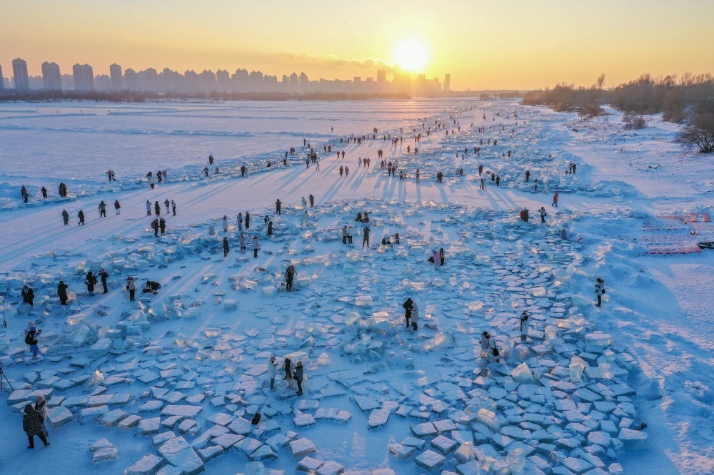 2024年1月7日，在封凍的松花江哈爾濱段，游客在日落時(shí)分的“鉆石海”游玩（無(wú)人機(jī)照片）。新華社記者 謝劍飛 攝