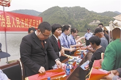 法院干警及相關(guān)部門工作人員對(duì)群眾進(jìn)行生態(tài)環(huán)境保護(hù)普法教育。