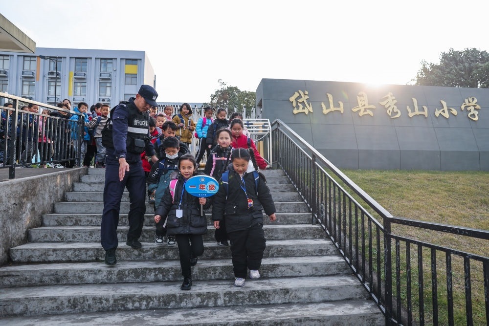 2023年12月20日，秀山派出所民警在秀山小學放學時間參與“護學崗”維持秩序，同時接獨自放學的學生去“民生小鋪”。浙江省舟山市岱山縣公安局秀山派出所聯(lián)合鄉(xiāng)鎮(zhèn)、社區(qū)成立“民生小鋪”，為當?shù)鼐用瘛⑼鈦韯展と藛T及其子女等服務，協(xié)助解決外來務工人員在工作、生活等方面的矛盾和問題，助力鄉(xiāng)鎮(zhèn)基層治理。新華社記者 徐昱 攝