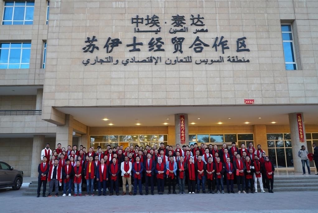 2024年2月11日，在位于埃及蘇伊士省的中埃·泰達(dá)蘇伊士經(jīng)貿(mào)合作區(qū)，中埃員工在合作區(qū)辦公大樓前合影拜年。新華社發(fā)（泰達(dá)合作區(qū)供圖）