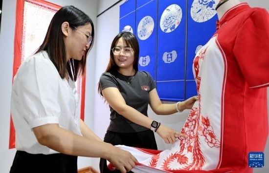 5月31日，在衡水市阜城縣一家剪紙工作室，游客在觀賞帶有剪紙?jiān)氐钠炫邸? width=