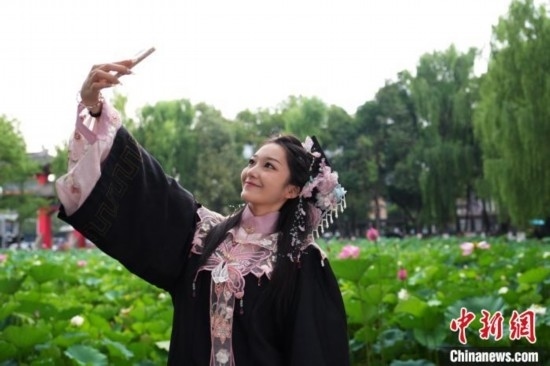6月19日，時值一年畢業(yè)季，四川大學(xué)望江校區(qū)荷花池里的荷花盛開，成為了畢業(yè)生們的打卡圣地，吸引了眾多畢業(yè)生拍照留念。圖為畢業(yè)生在荷花池邊拍照留念。中新社記者 安源 攝