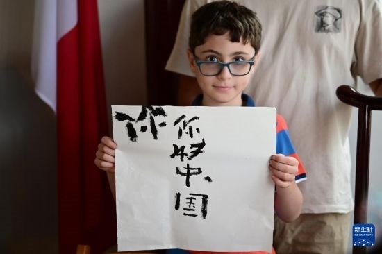 7月4日，在馬耳他桑塔露琪亞市的中國(guó)古典園林“靜園”，一名男孩展示他的書(shū)法作品。新華社發(fā)（喬納森·博格 攝）