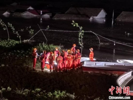  7月6日凌晨3時(shí)，在湖南岳陽(yáng)華容縣團(tuán)洲垸洞庭湖一線堤防，救援人員剛剛完成一次救援任務(wù)，遠(yuǎn)處是被淹的民房。中新社記者 白祖偕 攝