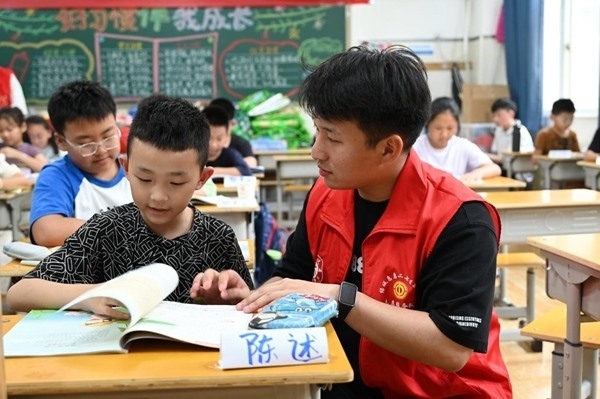 鄭州市二七區(qū)暑托班的志愿者輔導孩子寫作業(yè)。人民網(wǎng)記者王玉興攝