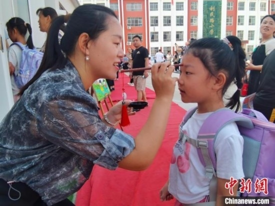 圖為衡水市利民路小學(xué)，老師為學(xué)生點(diǎn)朱砂痣，寓意開啟智慧。張松 攝