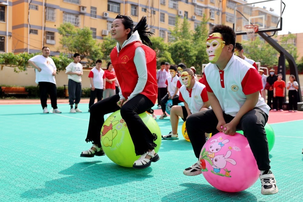 2024年5月17日，在山東省棗莊市市中區(qū)特殊教育中心，青年志愿者與智力障礙學(xué)生一起做游戲。新華社發(fā)（孫中喆攝）