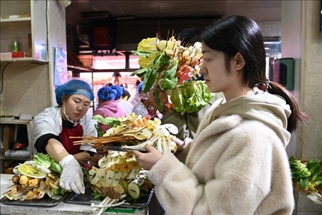 游客挑選好麻辣燙菜品后排隊(duì)等待加工。新華社記者 范培珅 攝