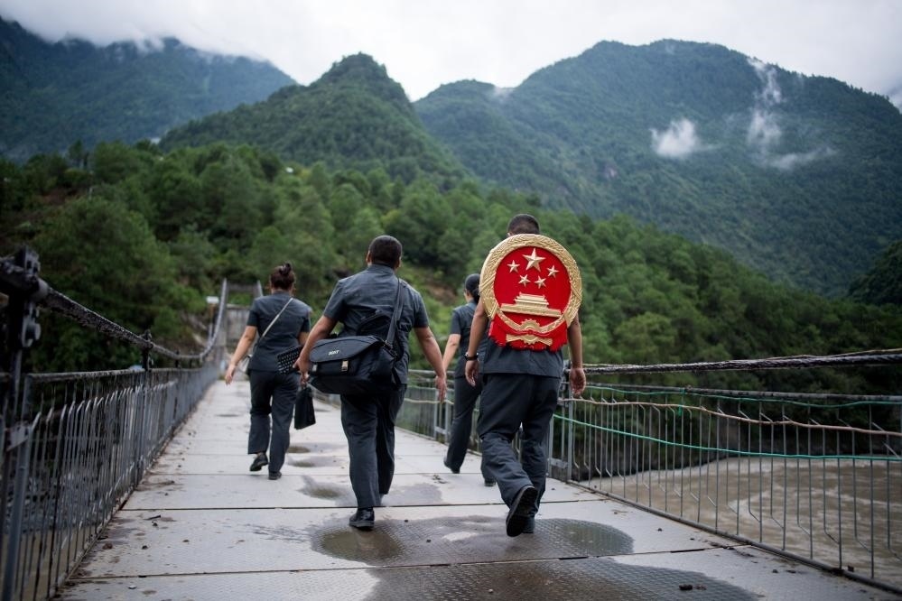 云南省怒江傈僳族自治州貢山縣人民法院法官鄧興背著國徽與同事們跨過怒江（2019年8月30日攝）。怒江高山峽谷眾多，交通不便，為方便群眾、更好地開展法律服務，背著國徽攀高山、過索橋、躲落石、鉆老林……成為鄧興法官的工作常態(tài)。新華社記者 江文耀 攝