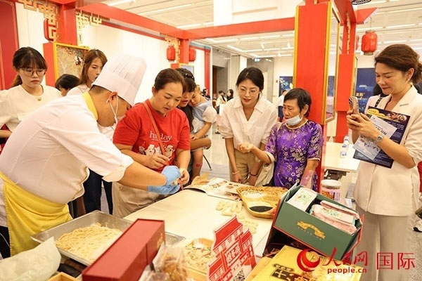 演出前，在天津桂發(fā)祥十八街麻花制作技藝非遺體驗展臺前，泰國民眾體驗天津麻花制作。人民網(wǎng)記者 楊一攝