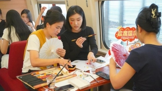 10月1日，旅客們?cè)贕1634次列車上給油紙傘作畫(huà)。新華社記者周義 攝