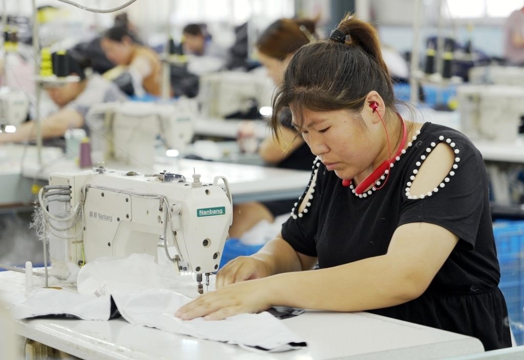 5月20日，村民在李寨村服裝加工廠內(nèi)忙碌。河南省周口市沈丘縣馮營(yíng)鎮(zhèn)李寨村地處豫東平原。近年來，乘著脫貧攻堅(jiān)與鄉(xiāng)村振興政策的東風(fēng)，李寨村積極探索產(chǎn)業(yè)發(fā)展模式，通過“龍頭企業(yè)+村集體經(jīng)濟(jì)+農(nóng)戶”的方式，逐漸發(fā)展形成肉牛養(yǎng)殖、設(shè)施農(nóng)業(yè)、服裝加工、康養(yǎng)民宿等產(chǎn)業(yè)，以產(chǎn)業(yè)振興助力鄉(xiāng)村振興。新華社記者 李嘉南 攝