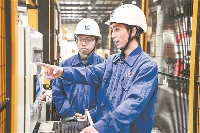 在廣西柳工機(jī)械股份有限公司生產(chǎn)車間內(nèi)，一名高級技師（右）給徒弟講解數(shù)控設(shè)備操作細(xì)節(jié)。新華社記者 曹祎銘攝