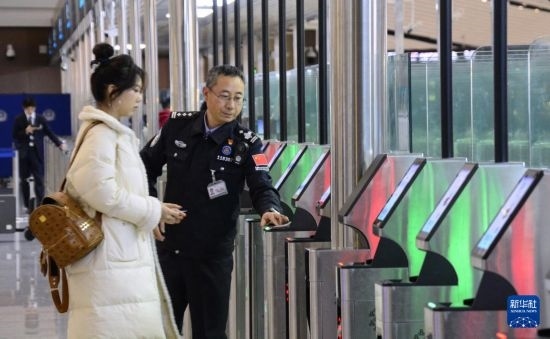 1月2日，大興機場邊檢站警察指導旅客使用自助出境設(shè)備。新華社記者 李欣 攝