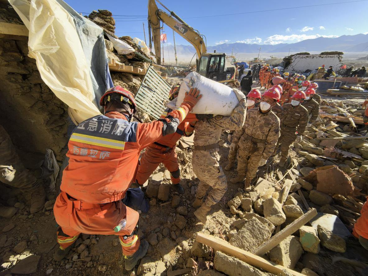 1月11日，定日縣長(zhǎng)所鄉(xiāng)古榮村，應(yīng)急消防等救援人員排隊(duì)接力搶運(yùn)掩埋在倒塌房屋下的群眾財(cái)物。人民日?qǐng)?bào)記者楊翹楚攝