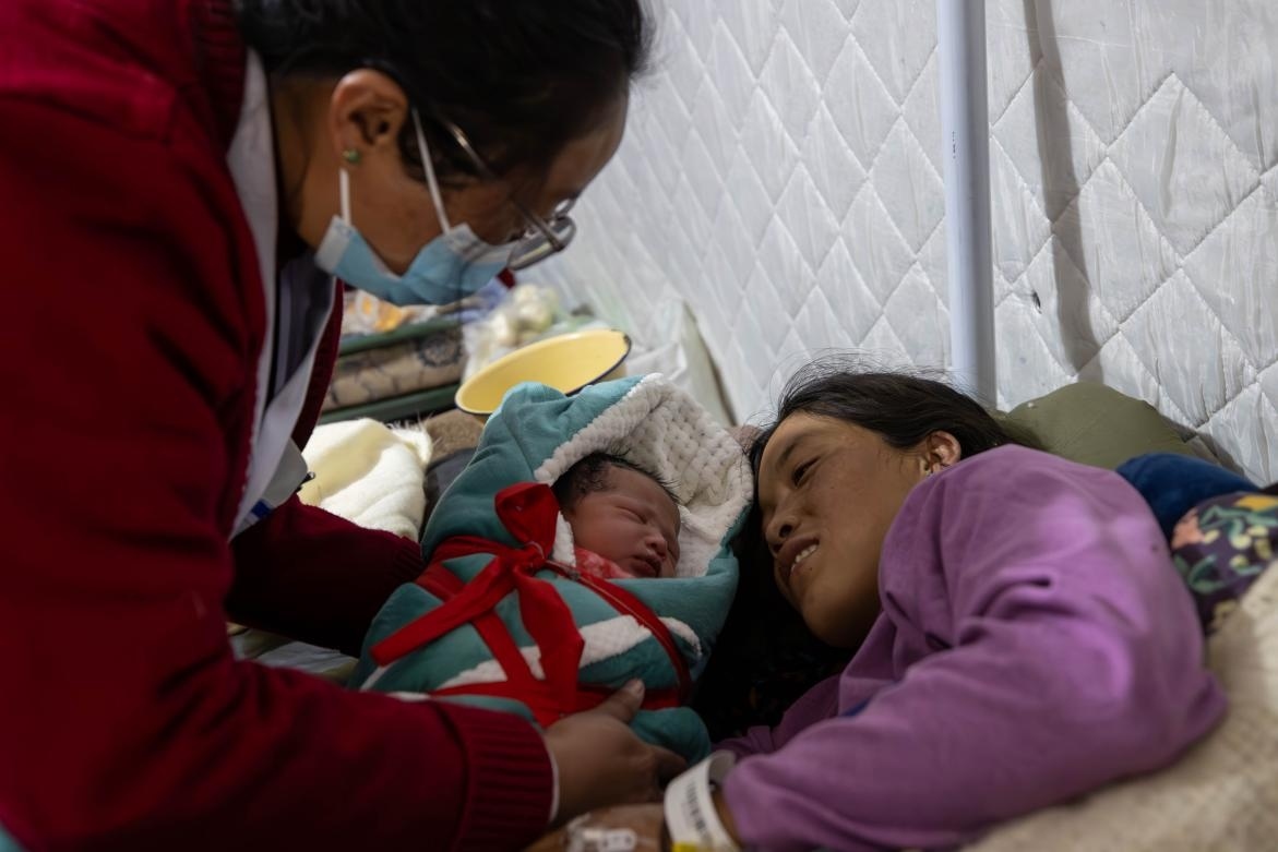 1月10日，定日縣中心醫(yī)院的婦產(chǎn)科醫(yī)生悉心照看一位母親和她懷里的新生兒。人民日?qǐng)?bào)記者張武軍攝