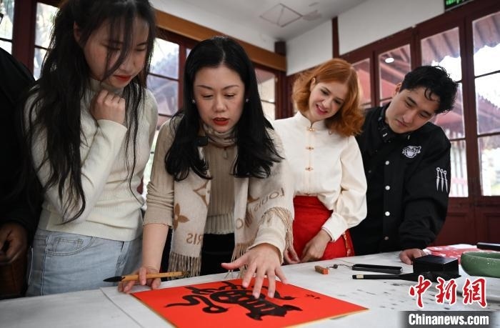 1月20日，西泠印社社員李硯（左二）為外籍留學(xué)生講述蛇年福字貼創(chuàng)作靈感。當(dāng)日，來(lái)自巴西、馬來(lái)西亞、加納、哈薩克斯坦的外籍留學(xué)生在浙江杭州西泠印社體驗(yàn)福貼、春聯(lián)和篆刻，感受古老的中國(guó)傳統(tǒng)文化。中新社記者 王剛 攝